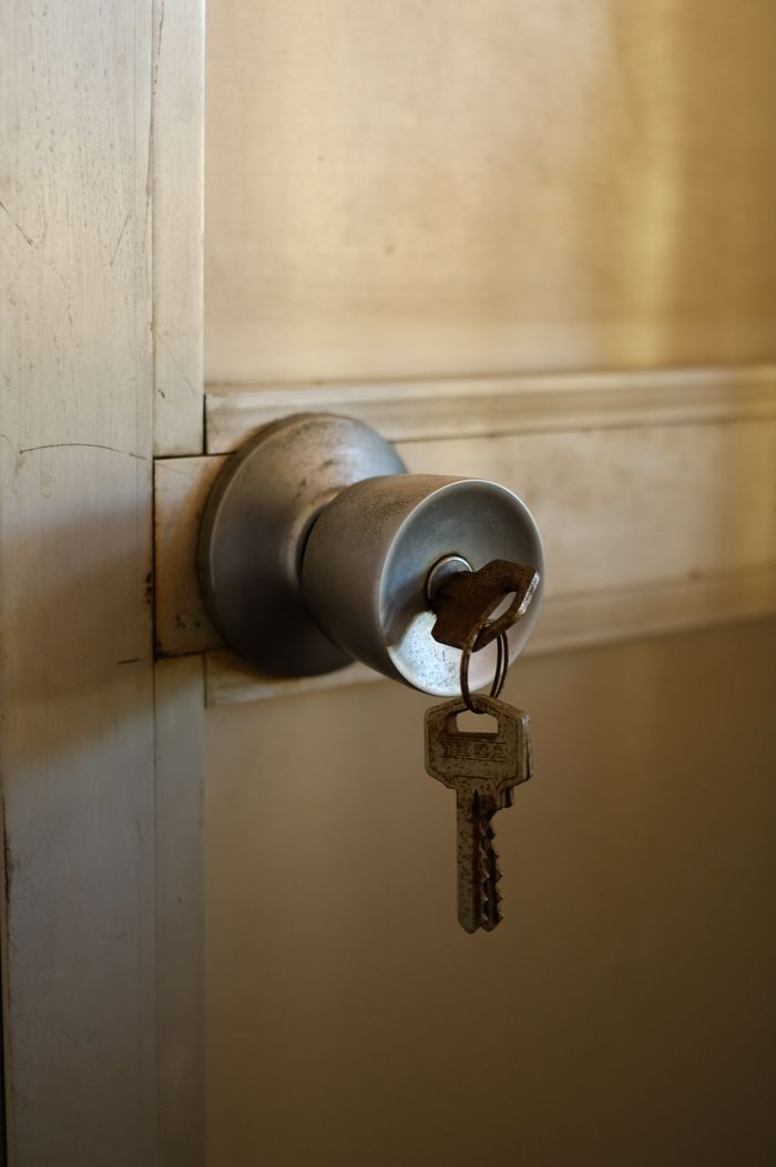 A key inserted in a metal door knob, symbolizing security and entry.